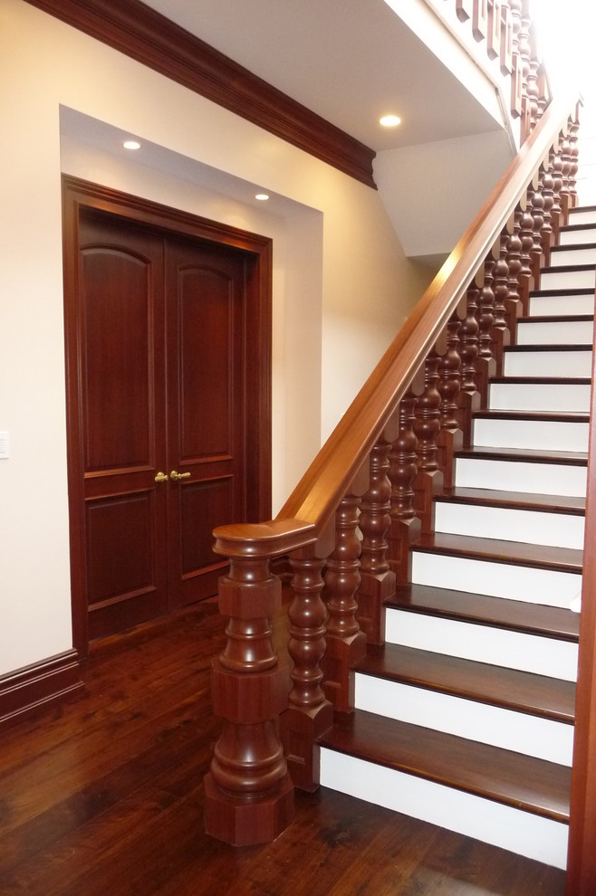 This is an example of an expansive traditional wood u-shaped staircase in New York with painted wood risers.
