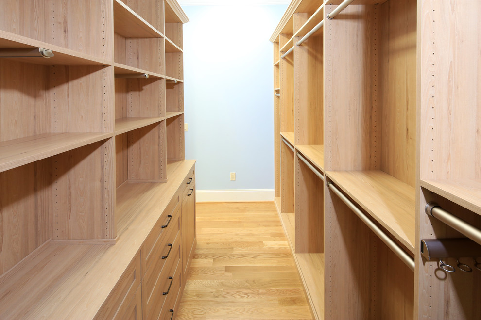 Photo of a mid-sized arts and crafts women's walk-in wardrobe in Atlanta with flat-panel cabinets, light wood cabinets and light hardwood floors.