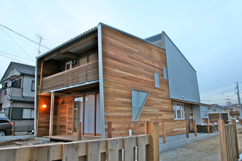 Photo of a contemporary two-storey brown house exterior in Other with wood siding, a shed roof and a metal roof.