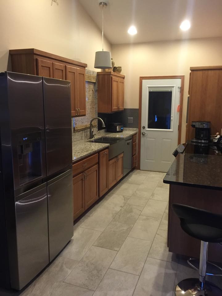 Mid-sized transitional single-wall medium tone wood floor and brown floor open concept kitchen photo with a farmhouse sink, recessed-panel cabinets, medium tone wood cabinets, quartz countertops and an island