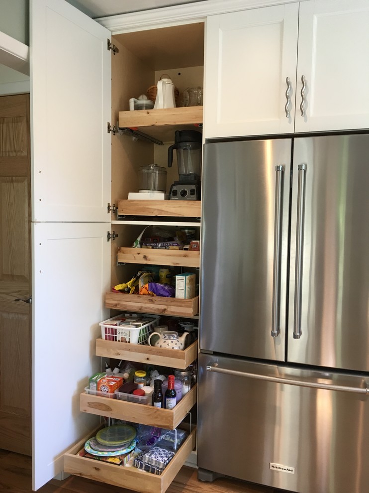 Mid-sized transitional l-shaped light wood floor enclosed kitchen photo with an undermount sink, flat-panel cabinets, white cabinets, granite countertops, white backsplash, subway tile backsplash, stainless steel appliances and no island
