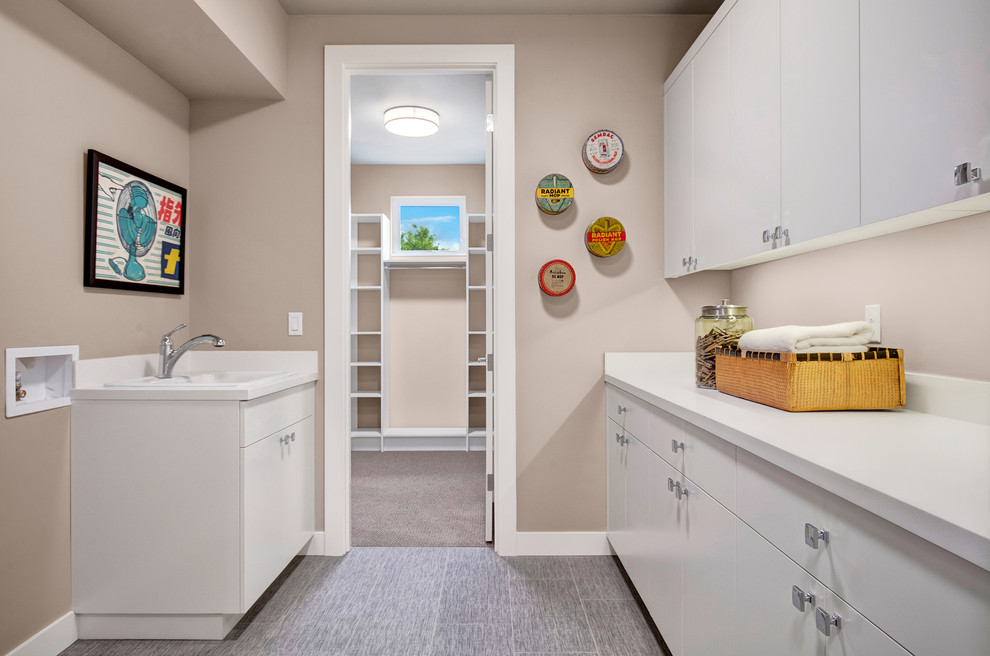 Photo of a contemporary laundry room in Seattle with an undermount sink, white cabinets, porcelain floors and a side-by-side washer and dryer.