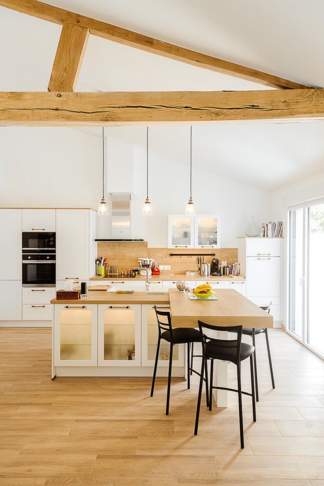 Design ideas for a large traditional galley open plan kitchen in Other with a single-bowl sink, wood worktops, brown splashback, wood splashback, stainless steel appliances, an island, brown floors, brown worktops and exposed beams.