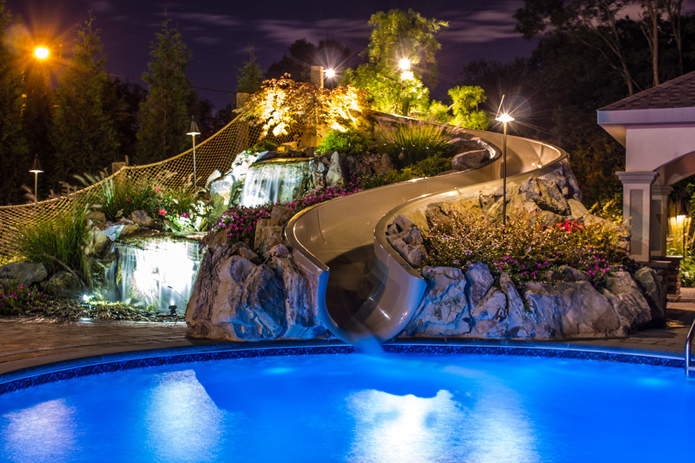 Photo of a large beach style backyard custom-shaped natural pool in New York with a water slide and concrete pavers.