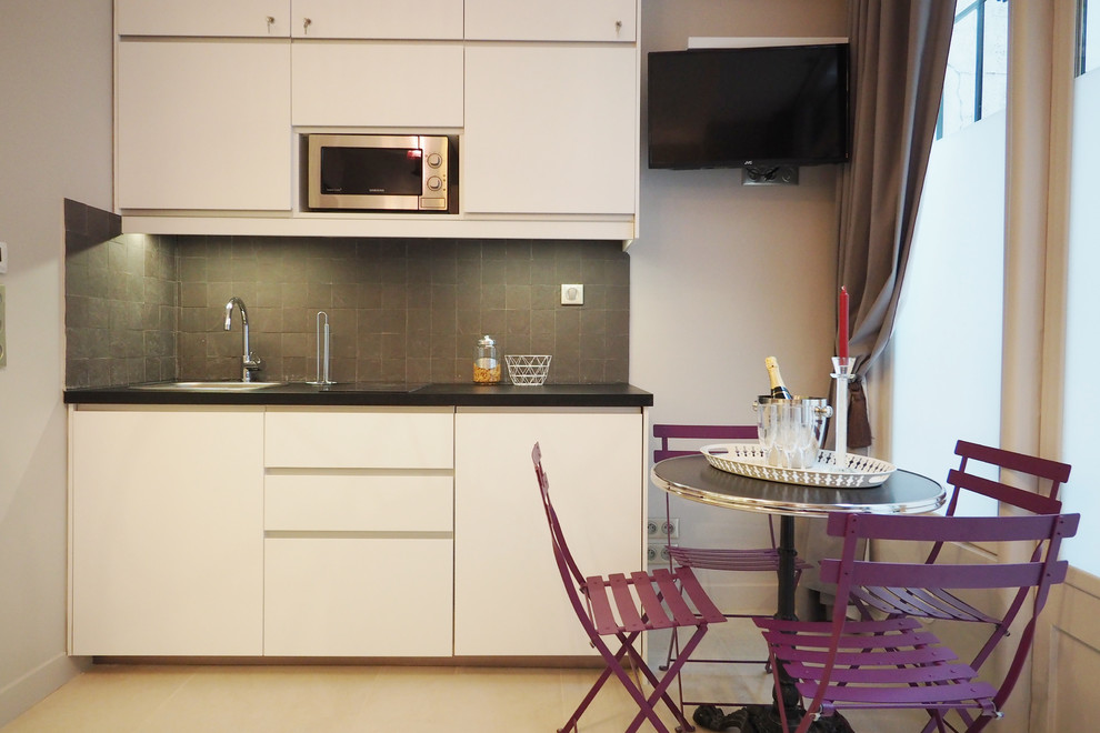 Photo of a small eclectic single-wall eat-in kitchen in Paris with a drop-in sink, white cabinets, grey splashback, ceramic splashback and no island.