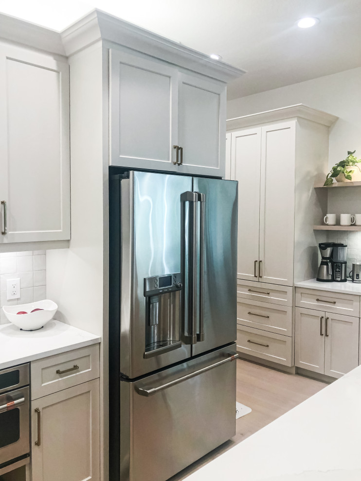 Kitchen - transitional l-shaped kitchen idea in Tampa with shaker cabinets, gray cabinets, quartz countertops, white backsplash, ceramic backsplash, stainless steel appliances, an island and white countertops