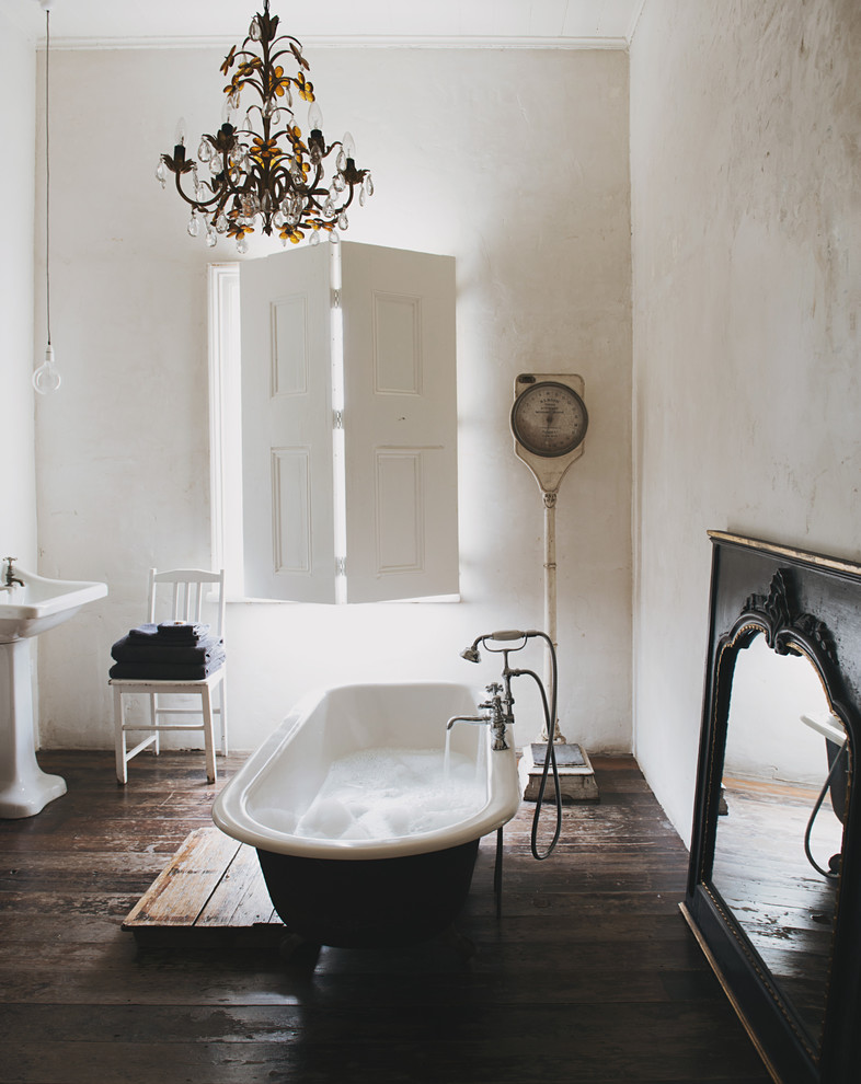 This is an example of a mid-sized eclectic 3/4 bathroom in Sydney with a pedestal sink, a claw-foot tub, white walls and dark hardwood floors.