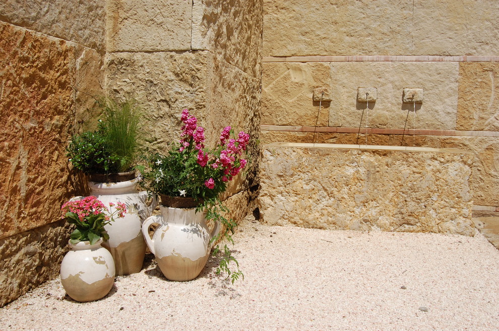 This is an example of a mediterranean patio in Dallas with a water feature.