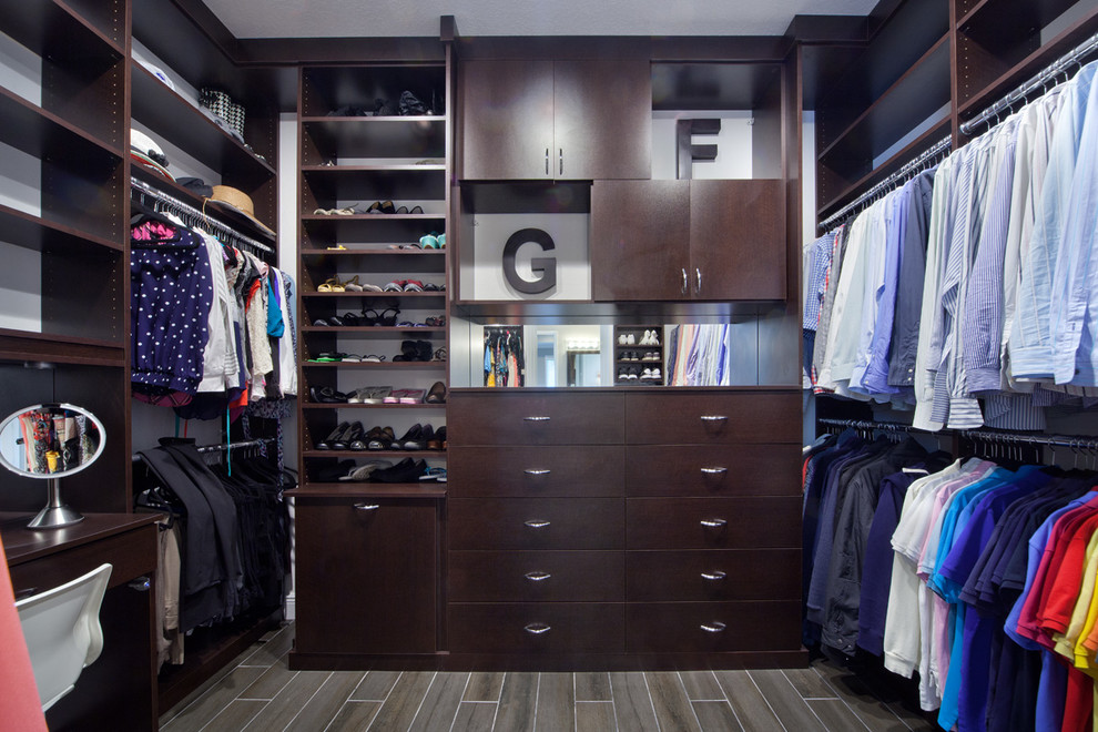 Photo of a mid-sized transitional gender-neutral walk-in wardrobe in Orlando with flat-panel cabinets, dark wood cabinets and porcelain floors.