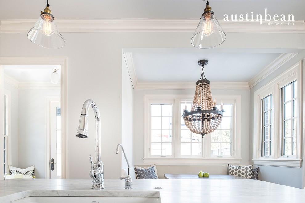 Transitional l-shaped medium tone wood floor eat-in kitchen photo with a farmhouse sink, glass-front cabinets, white cabinets, marble countertops, white backsplash, subway tile backsplash, stainless steel appliances, gray walls and an island