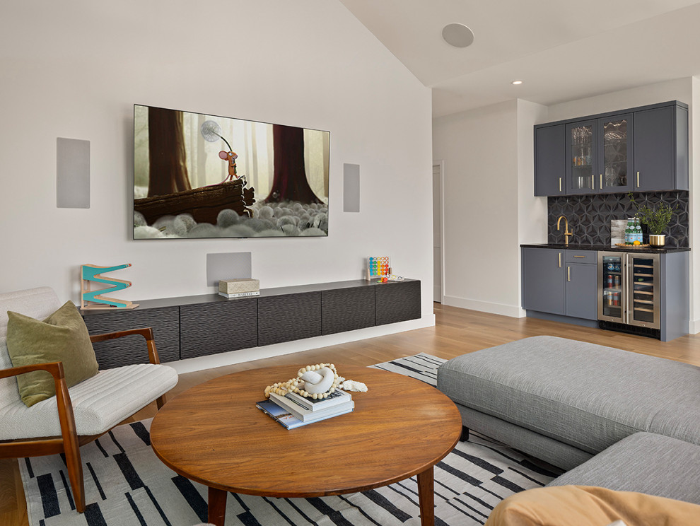 Mid-sized modern open concept family room in Minneapolis with a home bar, white walls, medium hardwood floors, a standard fireplace, brown floor and a wall-mounted tv.