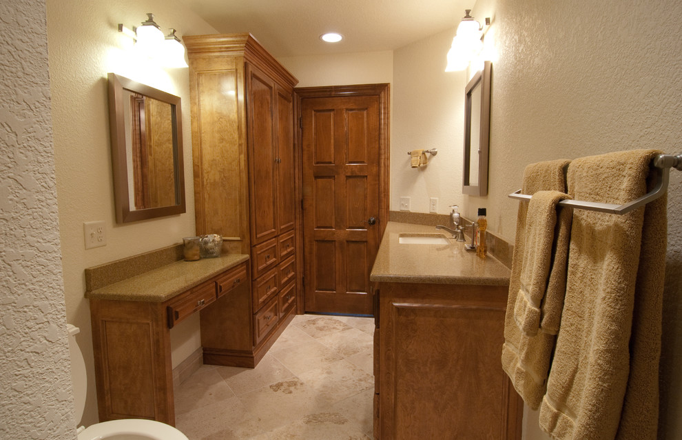 This is an example of a mid-sized transitional master bathroom in Milwaukee with recessed-panel cabinets, brown cabinets, an undermount tub, a shower/bathtub combo, a one-piece toilet, brown tile, beige walls, travertine floors, an undermount sink, granite benchtops, brown floor and a shower curtain.