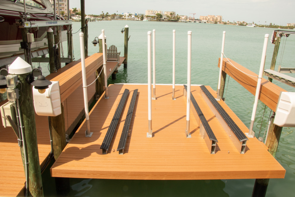 Large beach style backyard deck in Tampa with with dock and a roof extension.