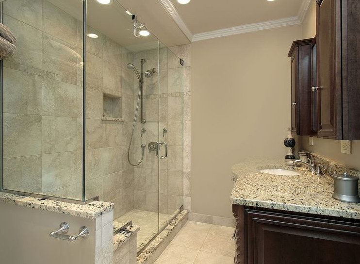 Photo of a mid-sized transitional 3/4 bathroom in New York with raised-panel cabinets, dark wood cabinets, an alcove shower, ceramic tile, an undermount sink, white floor, a hinged shower door, gray tile, grey walls, porcelain floors, granite benchtops and a single vanity.
