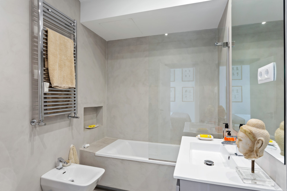Mid-sized contemporary 3/4 bathroom in Madrid with a shower/bathtub combo, gray tile, an integrated sink and white benchtops.