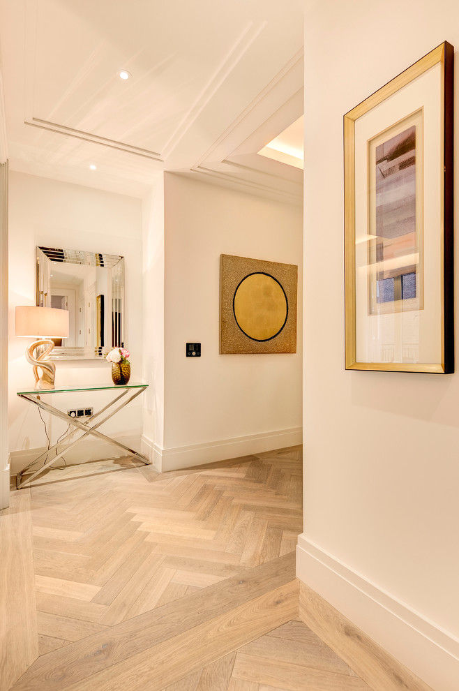 Design ideas for a mid-sized transitional hallway in London with white walls and light hardwood floors.