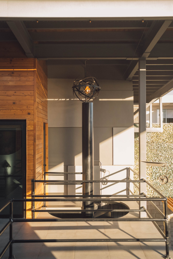 Photo of a large industrial metal spiral staircase in Other with metal risers, metal railing and wood walls.