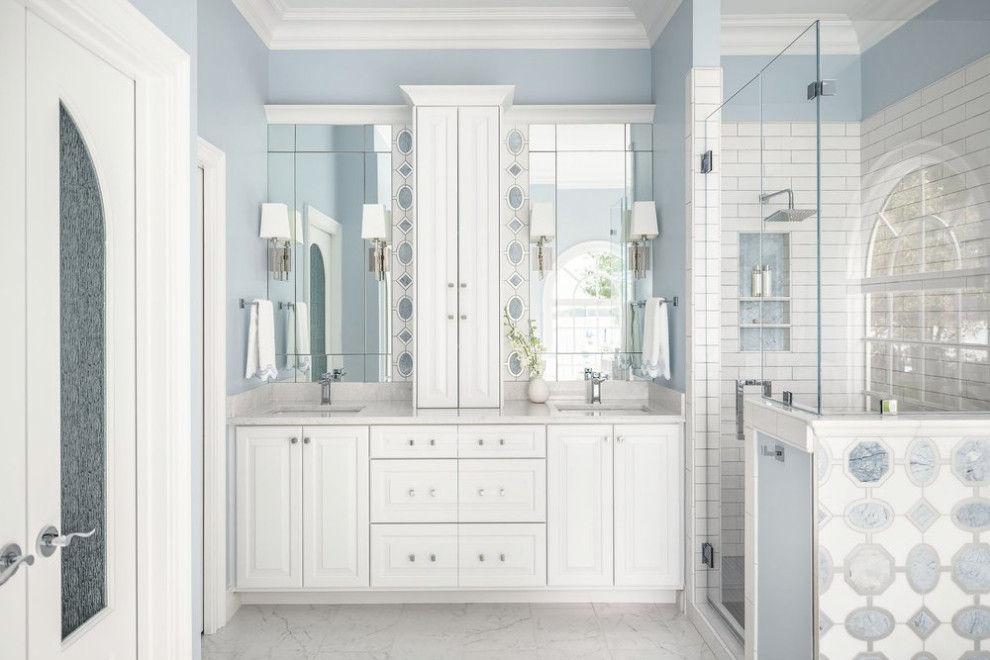 Design ideas for a mid-sized beach style master bathroom in Charlotte with raised-panel cabinets, white cabinets, a freestanding tub, an alcove shower, a two-piece toilet, white tile, ceramic tile, blue walls, ceramic floors, an undermount sink, engineered quartz benchtops, white floor, a hinged shower door, white benchtops, a niche, a double vanity, a built-in vanity, recessed and decorative wall panelling.