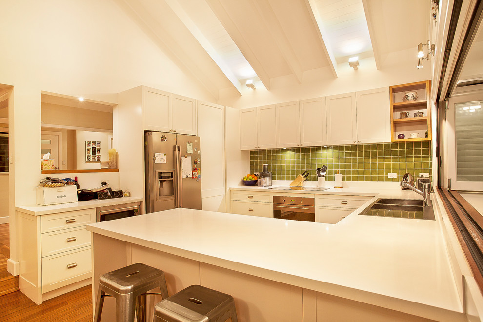 Photo of a large transitional u-shaped eat-in kitchen in Sydney with beige cabinets, green splashback, ceramic splashback, stainless steel appliances, a drop-in sink, beaded inset cabinets and medium hardwood floors.