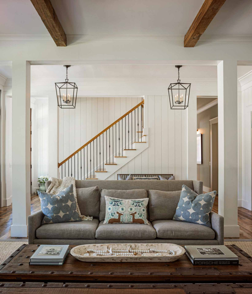 Immagine di un soggiorno country con pareti bianche, pavimento in legno massello medio, pavimento marrone, travi a vista e pareti in perlinato