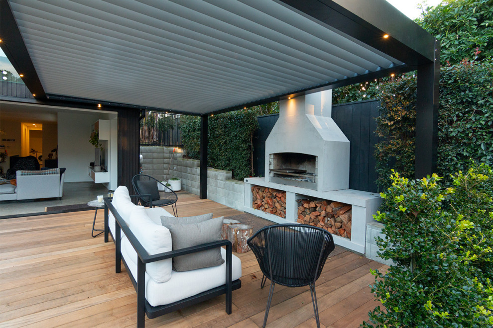 Design ideas for a mid-sized backyard deck in Auckland with with fireplace and a pergola.