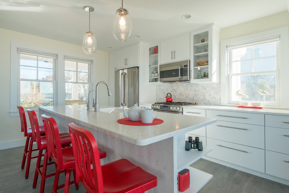 Beach style galley kitchen in Boston with an undermount sink, white cabinets, quartz benchtops, multi-coloured splashback, matchstick tile splashback, stainless steel appliances, medium hardwood floors, with island and flat-panel cabinets.