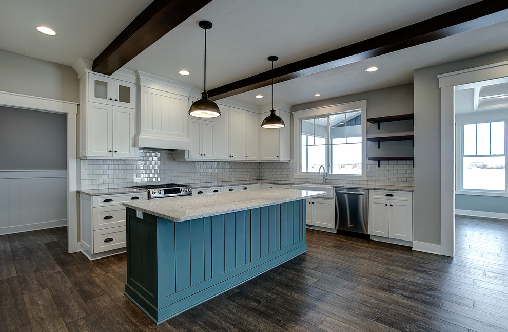 Photo of a mid-sized arts and crafts u-shaped kitchen pantry in Grand Rapids with a farmhouse sink, shaker cabinets, white cabinets, granite benchtops, white splashback, ceramic splashback, stainless steel appliances, medium hardwood floors, with island and brown floor.