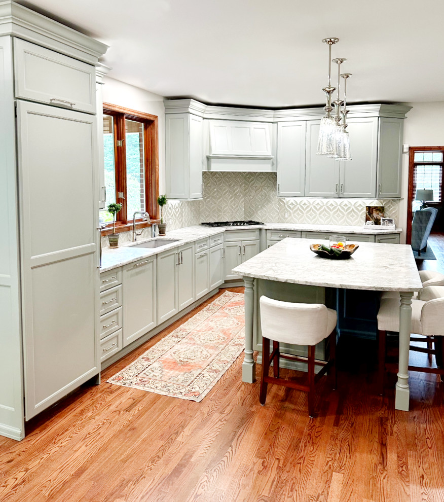 Eat-in kitchen - transitional l-shaped medium tone wood floor eat-in kitchen idea with shaker cabinets, green cabinets, quartzite countertops, porcelain backsplash, paneled appliances and an island