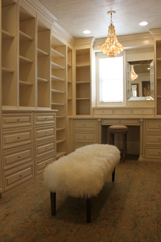 This is an example of a traditional women's walk-in wardrobe in Orange County with carpet.