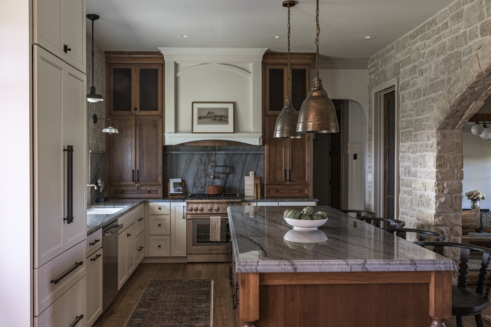 Mid-sized french country l-shaped medium tone wood floor and brown floor kitchen photo in Other with an undermount sink, quartzite countertops, stainless steel appliances, an island, gray countertops, recessed-panel cabinets, white cabinets, gray backsplash and stone slab backsplash
