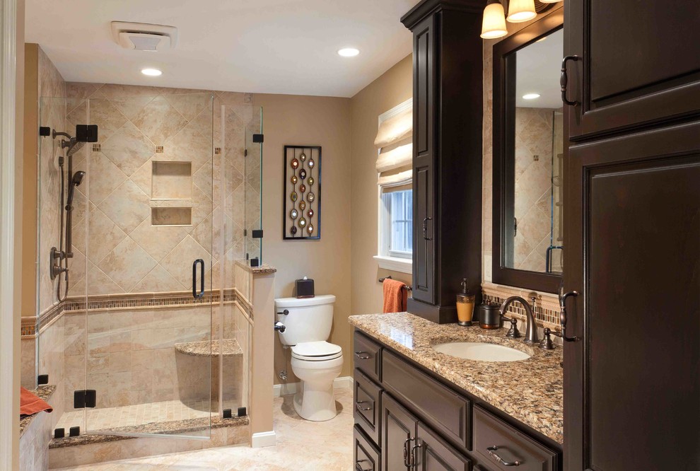 This is an example of a mid-sized traditional master bathroom in Other with raised-panel cabinets, dark wood cabinets, a corner shower, a two-piece toilet, ceramic tile, beige walls, travertine floors, an undermount sink and granite benchtops.