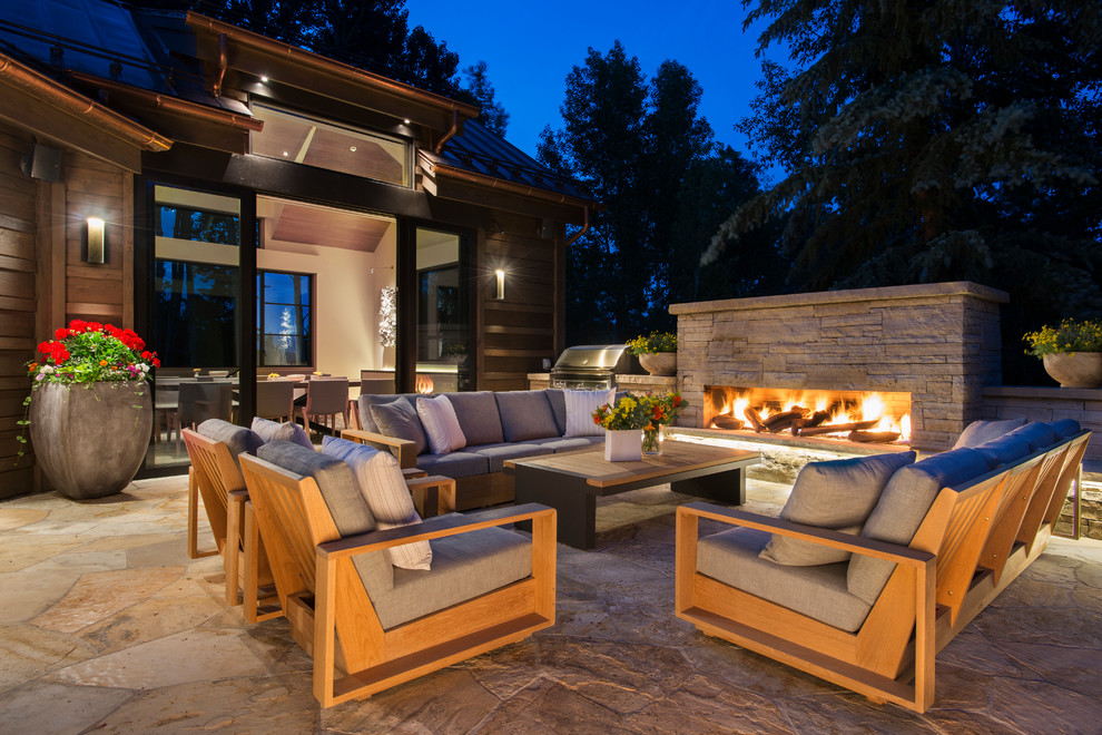 Photo of a contemporary patio in Denver with natural stone pavers, no cover and with fireplace.