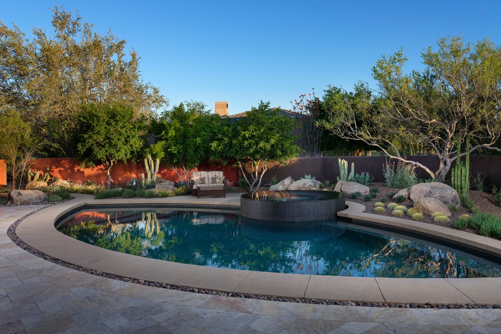 This is an example of a mid-sized contemporary backyard custom-shaped pool in Phoenix with tile.