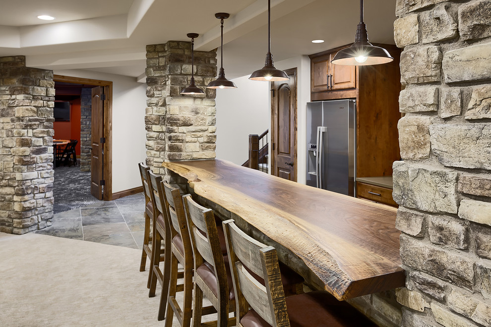 Mid-sized traditional galley seated home bar in Denver with an integrated sink, flat-panel cabinets, dark wood cabinets, wood benchtops, beige splashback, ceramic floors, beige floor, brown benchtop and timber splashback.