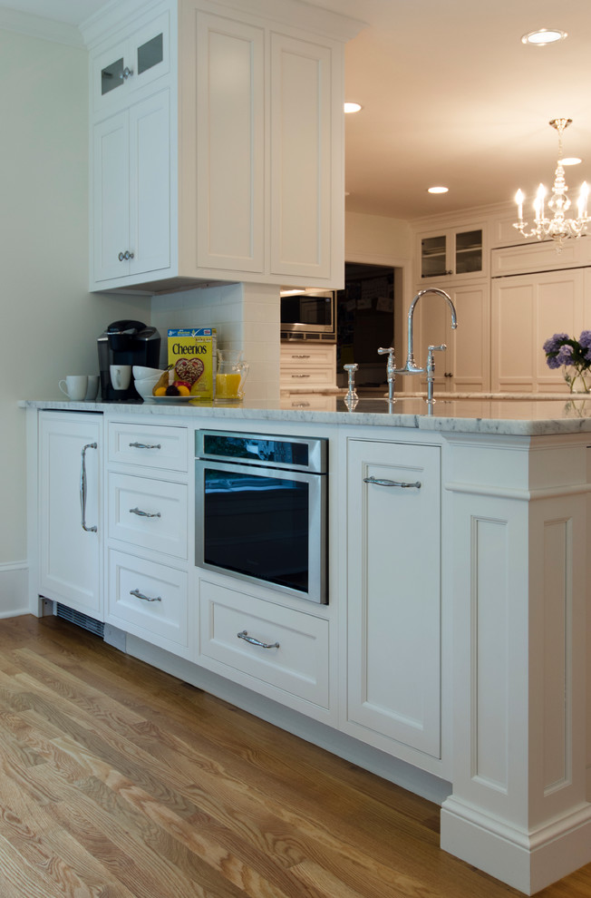 Eat-in kitchen - transitional u-shaped medium tone wood floor eat-in kitchen idea in Boston with a farmhouse sink, beaded inset cabinets, white cabinets, marble countertops, white backsplash, subway tile backsplash, stainless steel appliances and an island