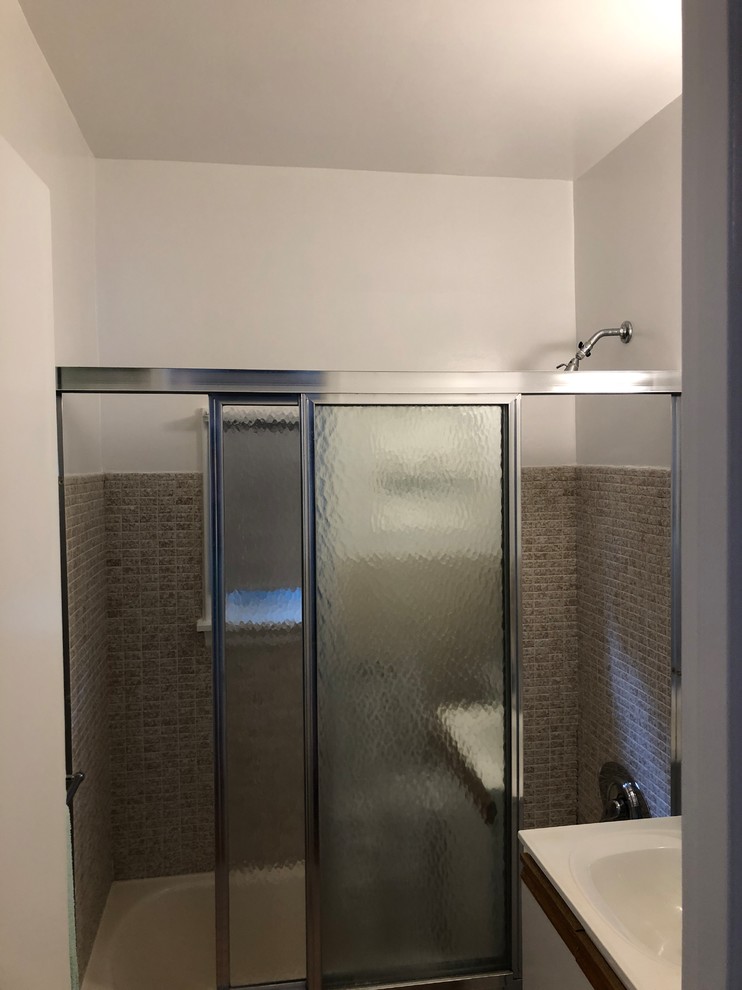 Mid-sized midcentury bathroom in Toronto with white cabinets, an alcove tub, a shower/bathtub combo, a one-piece toilet, brown tile, ceramic tile, white walls, ceramic floors, an integrated sink, solid surface benchtops, pink floor, a sliding shower screen and beige benchtops.