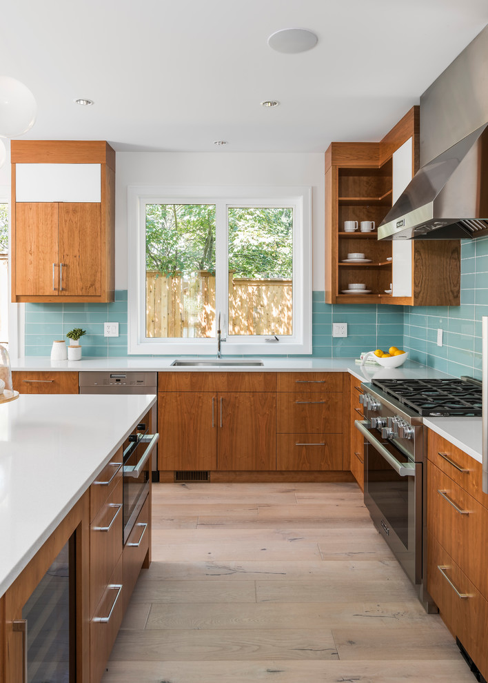 Design ideas for a mid-sized contemporary l-shaped kitchen in Other with an undermount sink, flat-panel cabinets, medium wood cabinets, quartz benchtops, blue splashback, stainless steel appliances, light hardwood floors, with island, white benchtop, glass tile splashback and beige floor.