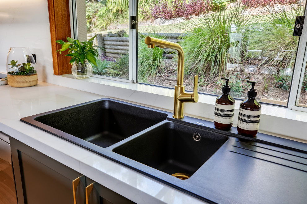 Inspiration for a large transitional l-shaped medium tone wood floor and multicolored floor eat-in kitchen remodel in Sydney with a drop-in sink, shaker cabinets, green cabinets, quartz countertops, white backsplash, quartz backsplash, black appliances, an island and white countertops