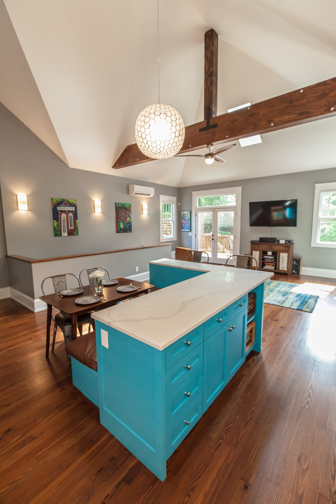 Photo of an eclectic l-shaped eat-in kitchen in Atlanta with a farmhouse sink, shaker cabinets, white cabinets, quartz benchtops, grey splashback, porcelain splashback, stainless steel appliances, medium hardwood floors, with island and white benchtop.