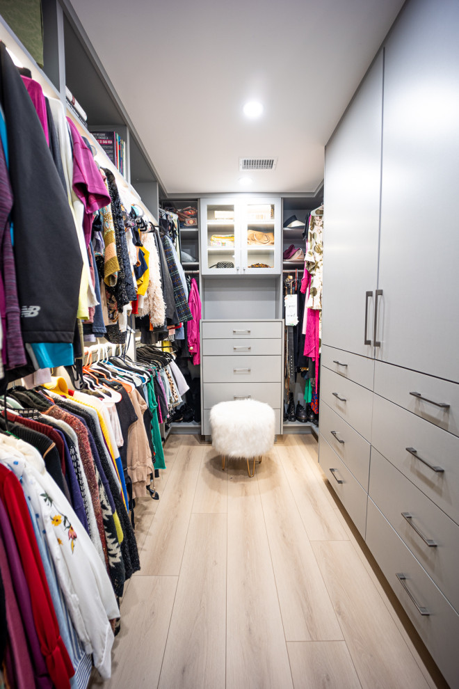 Diseño de armario vestidor minimalista pequeño con armarios con paneles lisos, puertas de armario grises, suelo vinílico y suelo marrón