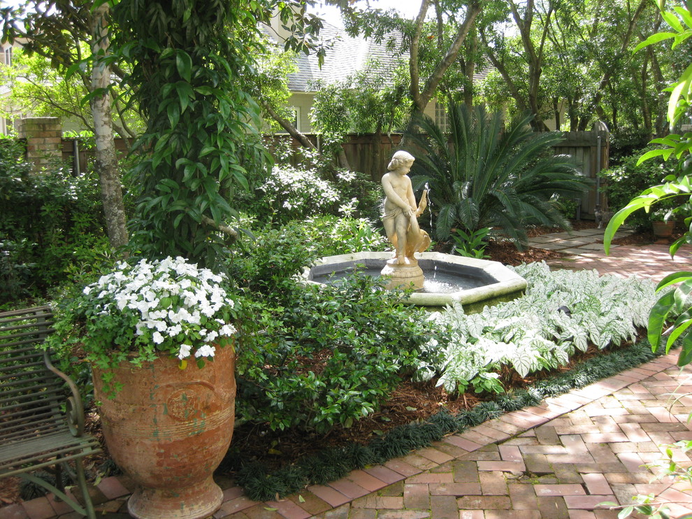 Inspiration for a mid-sized transitional side yard partial sun formal garden for summer in New Orleans with brick pavers and a water feature.