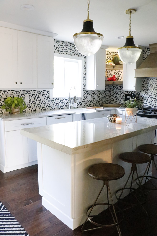Photo of a mid-sized eclectic l-shaped separate kitchen in St Louis with a farmhouse sink, shaker cabinets, white cabinets, marble benchtops, multi-coloured splashback, ceramic splashback, stainless steel appliances, dark hardwood floors, with island, brown floor and white benchtop.