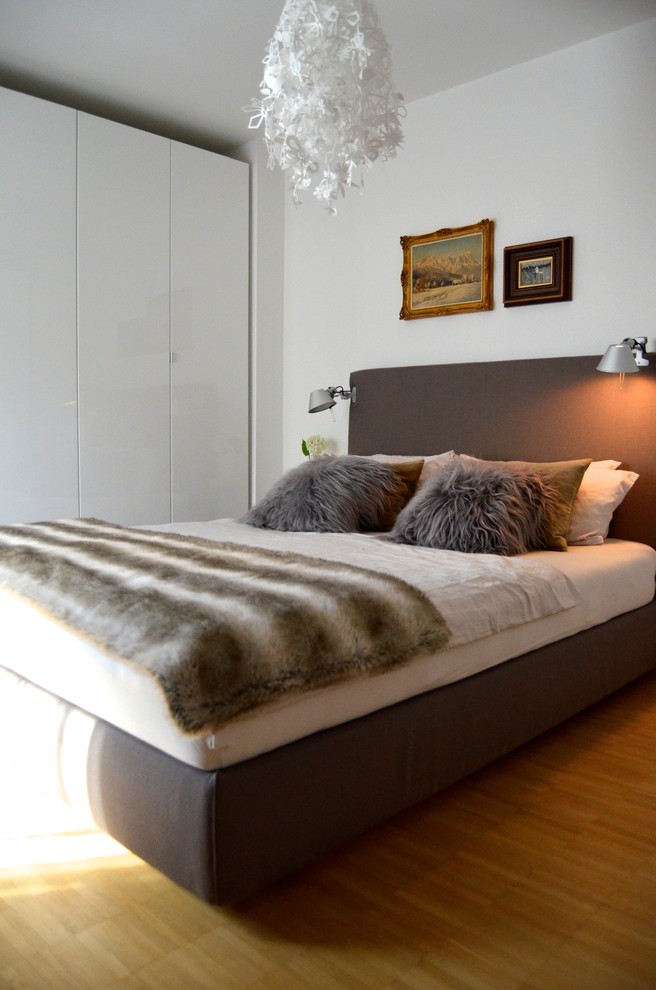 Design ideas for a mid-sized contemporary bedroom in Munich with light hardwood floors, white walls and no fireplace.