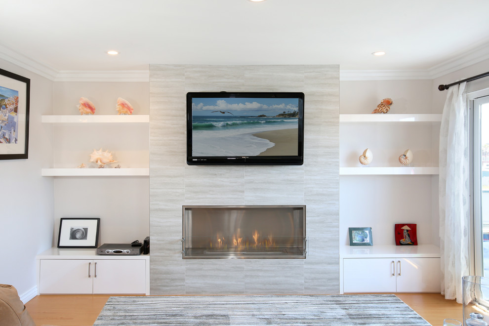 Photo of a mid-sized modern enclosed living room in Los Angeles with beige walls, light hardwood floors, a hanging fireplace, a tile fireplace surround and a wall-mounted tv.