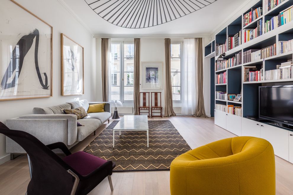 Design ideas for a contemporary family room in Paris with a library, white walls, light hardwood floors, no fireplace and a built-in media wall.
