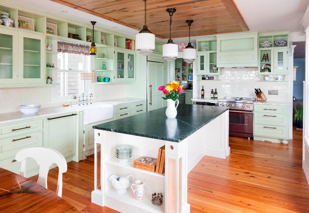 This is an example of a beach style kitchen in Boston with a farmhouse sink, green cabinets, panelled appliances and with island.