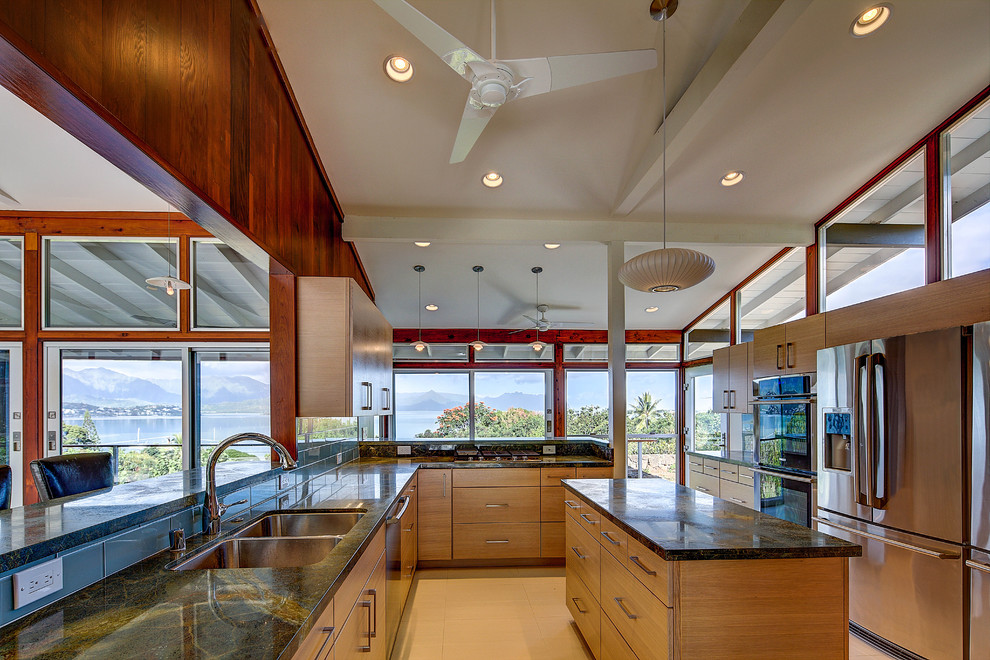 This is an example of a large midcentury u-shaped eat-in kitchen in Hawaii with a double-bowl sink, flat-panel cabinets, light wood cabinets, granite benchtops, stainless steel appliances, ceramic floors, with island and beige floor.