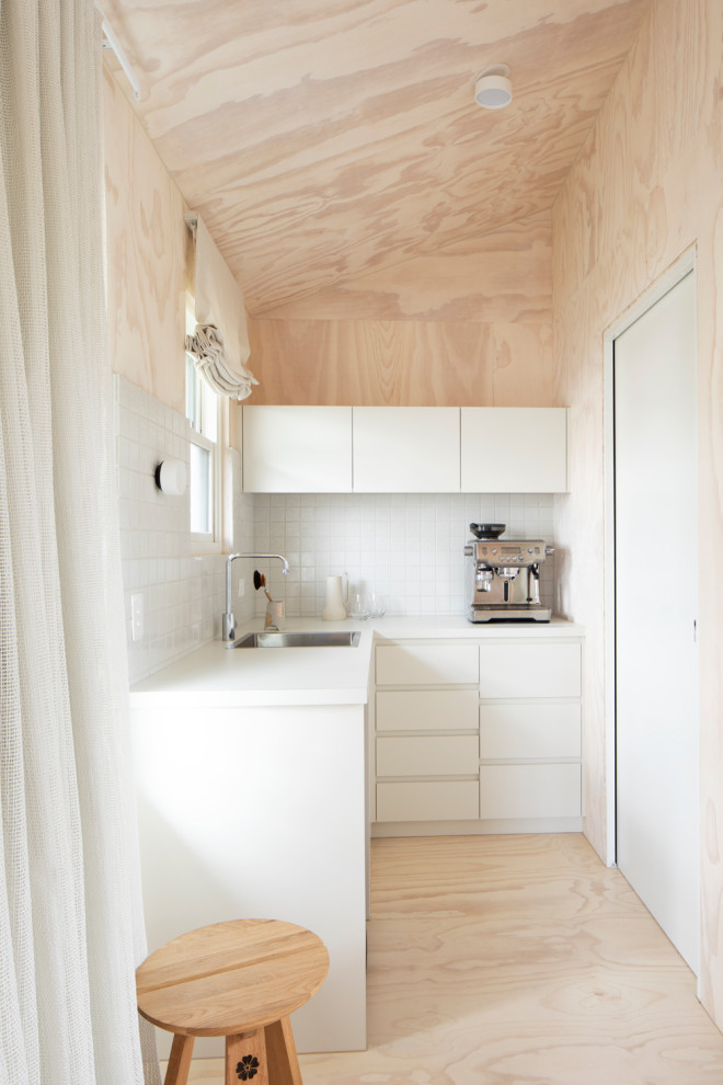 Idéer för små funkis vitt kök, med en integrerad diskho, släta luckor, vita skåp, laminatbänkskiva, vitt stänkskydd, stänkskydd i mosaik, rostfria vitvaror, målat trägolv och vitt golv