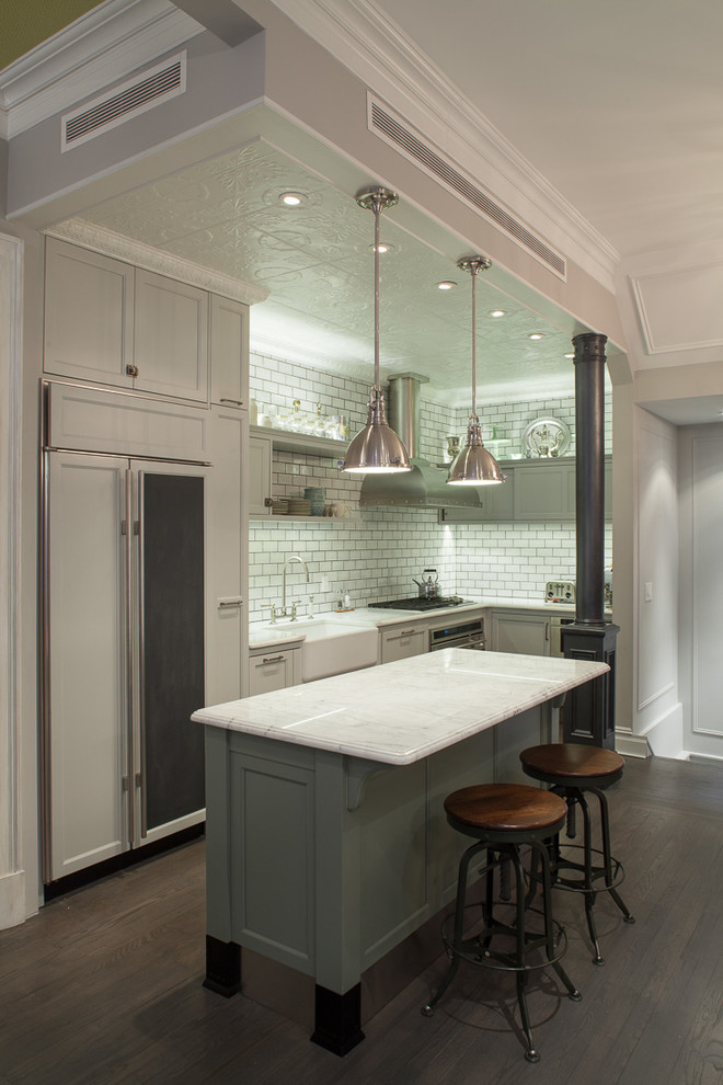 Design ideas for a small traditional l-shaped kitchen in New York with a farmhouse sink, recessed-panel cabinets, grey cabinets, white splashback, subway tile splashback, panelled appliances, dark hardwood floors and with island.
