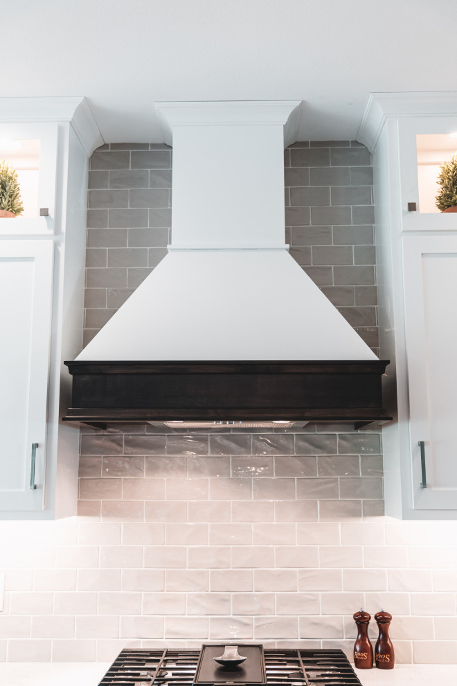 Example of a large transitional l-shaped vinyl floor and brown floor kitchen pantry design with an undermount sink, shaker cabinets, white cabinets, quartz countertops, gray backsplash, subway tile backsplash, stainless steel appliances, an island and white countertops